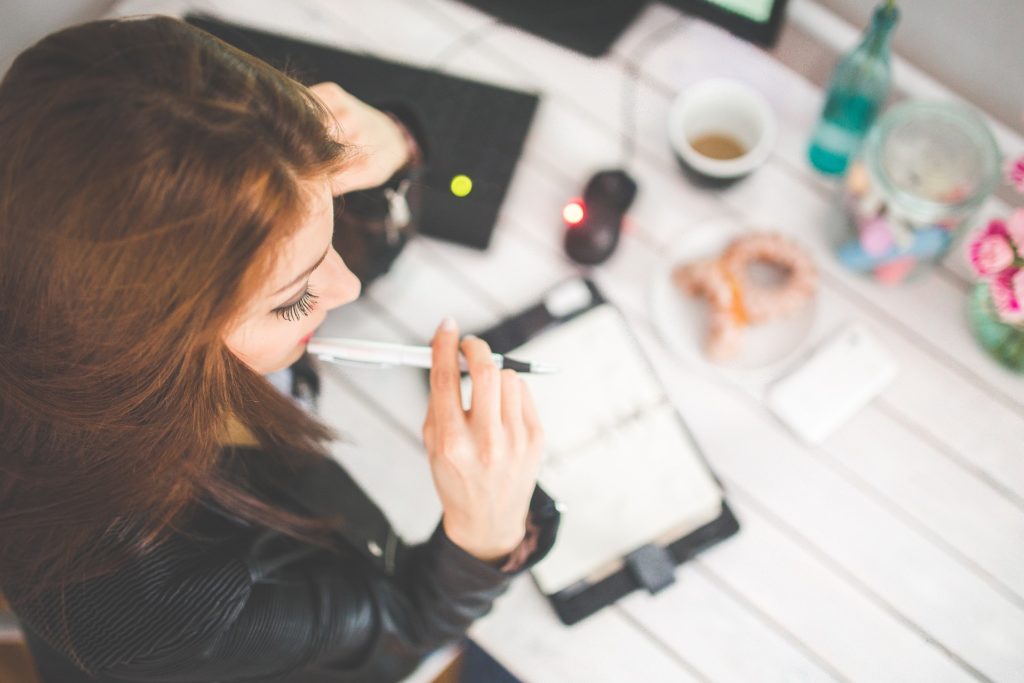 a girl holding a pen in her mouth, studying for an exam